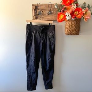 Black Athleta tapered windbreaker joggers with drawstring and zipper pockets